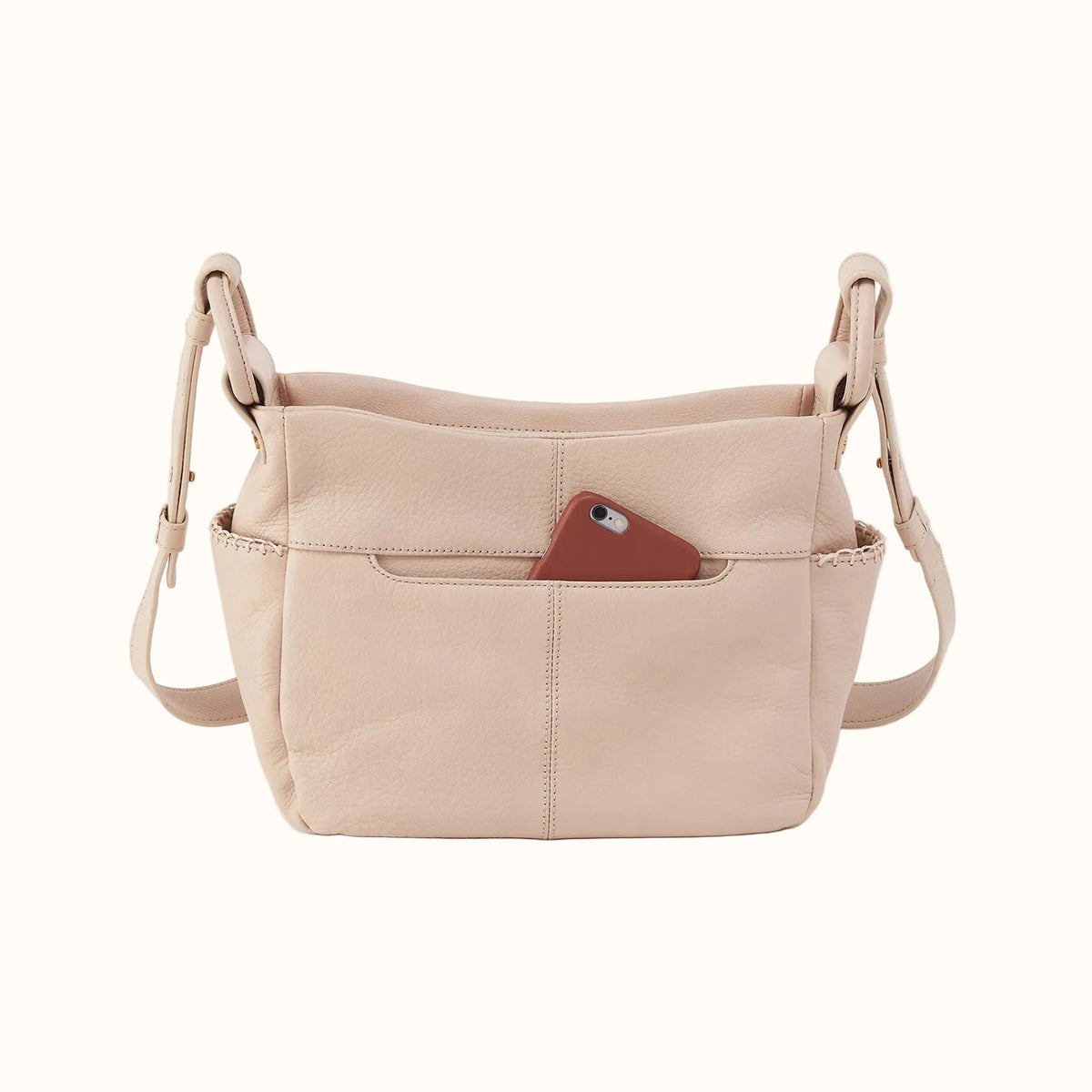 A light beige leather shoulder bag with a front pocket holding a brown smartphone, shown against a plain light gray background.